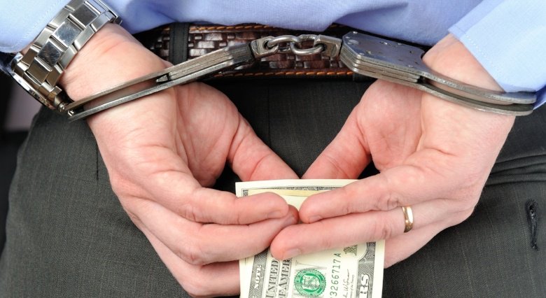 Employee in handcuffs holding money